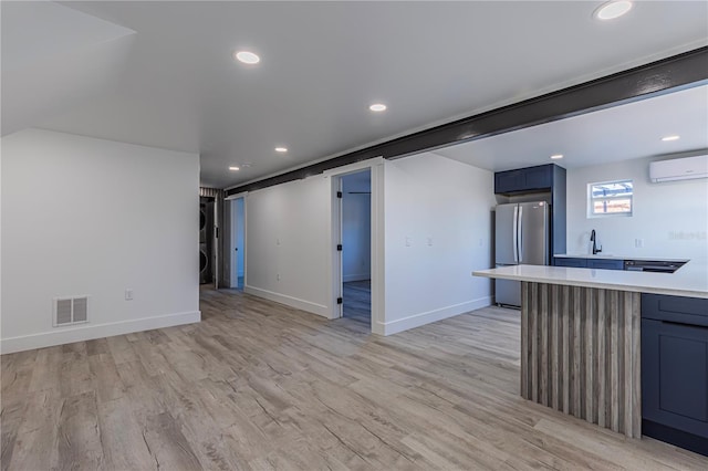 interior space with visible vents, light countertops, blue cabinetry, freestanding refrigerator, and a wall mounted air conditioner