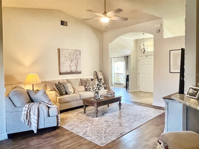 living room featuring visible vents, high vaulted ceiling, dark wood finished floors, arched walkways, and ceiling fan