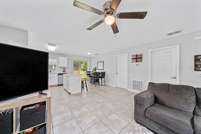 living area with light tile patterned floors, ceiling fan, visible vents, and baseboards