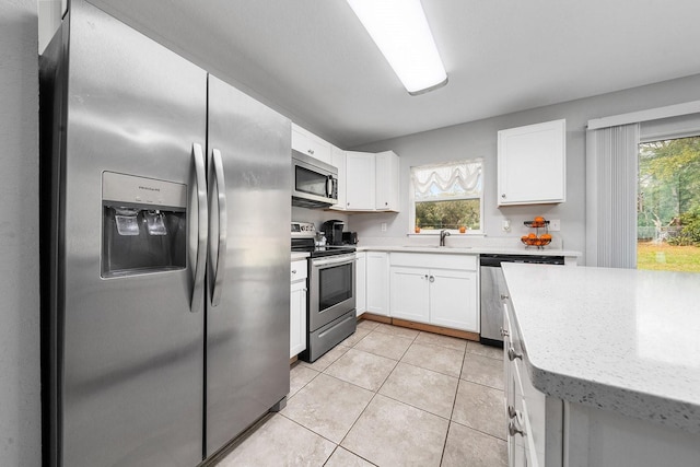 kitchen featuring stainless steel appliances, white cabinets, a sink, and light tile patterned floors