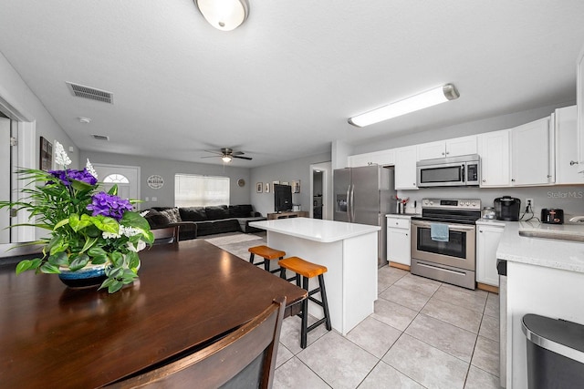 kitchen featuring white cabinets, appliances with stainless steel finishes, open floor plan, and light countertops