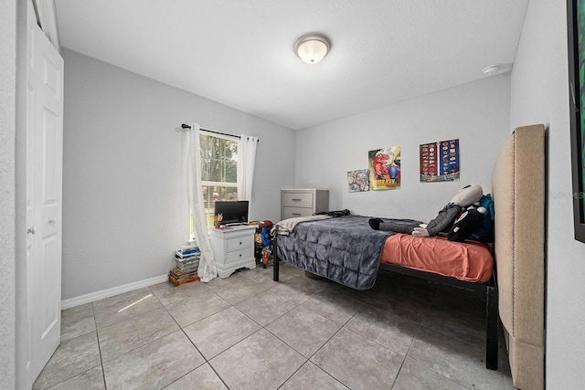 bedroom with baseboards and light tile patterned floors