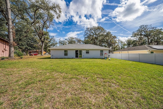 back of property featuring fence and a lawn