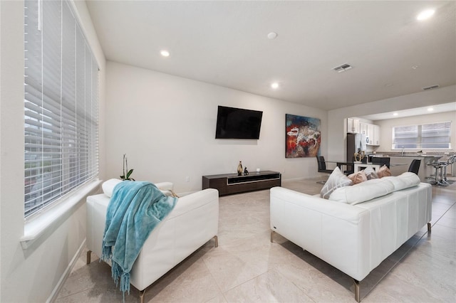 living area with baseboards, visible vents, and recessed lighting