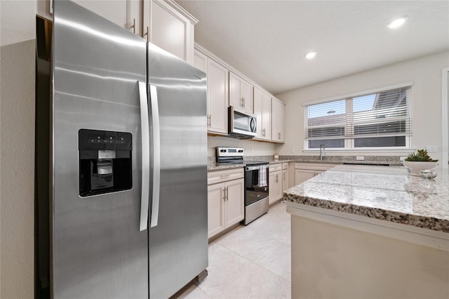 kitchen featuring light stone counters, recessed lighting, stainless steel appliances, a sink, and white cabinetry