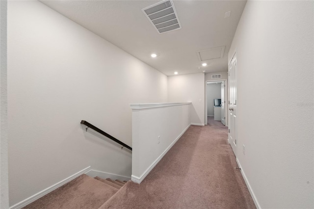 corridor with attic access, visible vents, baseboards, an upstairs landing, and carpet floors