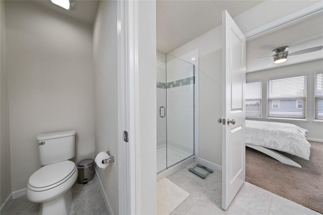 ensuite bathroom with toilet, a stall shower, ceiling fan, ensuite bath, and baseboards