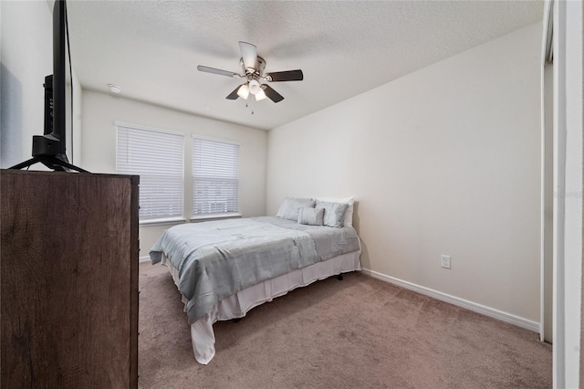 bedroom featuring light colored carpet, ceiling fan, a textured ceiling, and baseboards