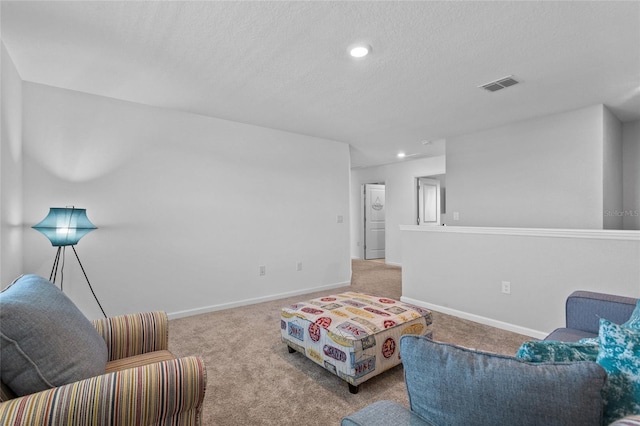 living area with carpet, visible vents, a textured ceiling, and baseboards