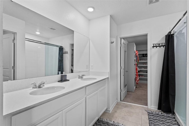 full bath featuring double vanity, a shower stall, a walk in closet, and a sink