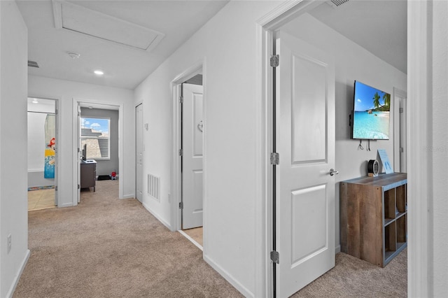 corridor with attic access, carpet flooring, visible vents, and baseboards