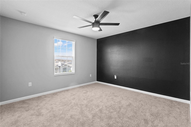 carpeted empty room with ceiling fan, a textured ceiling, and baseboards