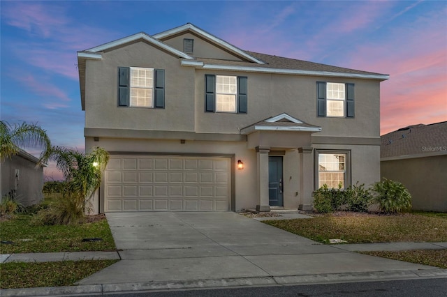 traditional home featuring a garage, concrete driveway, and stucco siding