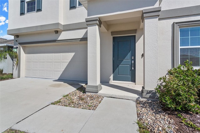 property entrance featuring a garage, driveway, and stucco siding