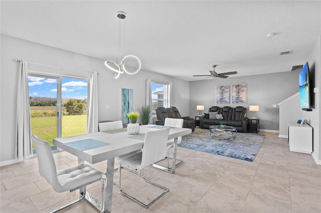 dining area featuring ceiling fan with notable chandelier, a textured ceiling, visible vents, and baseboards