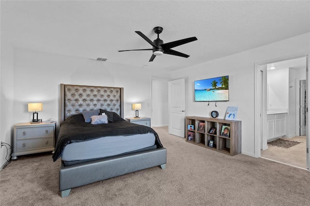 bedroom featuring visible vents, ensuite bath, ceiling fan, a textured ceiling, and carpet flooring