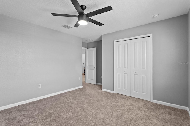 unfurnished bedroom with a textured ceiling, carpet flooring, visible vents, baseboards, and a closet