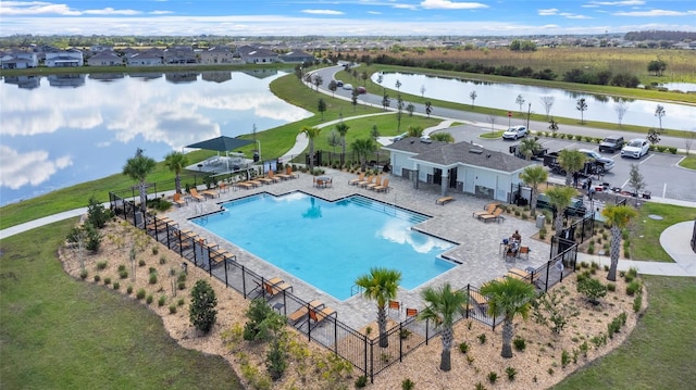 community pool featuring a patio, a water view, and fence