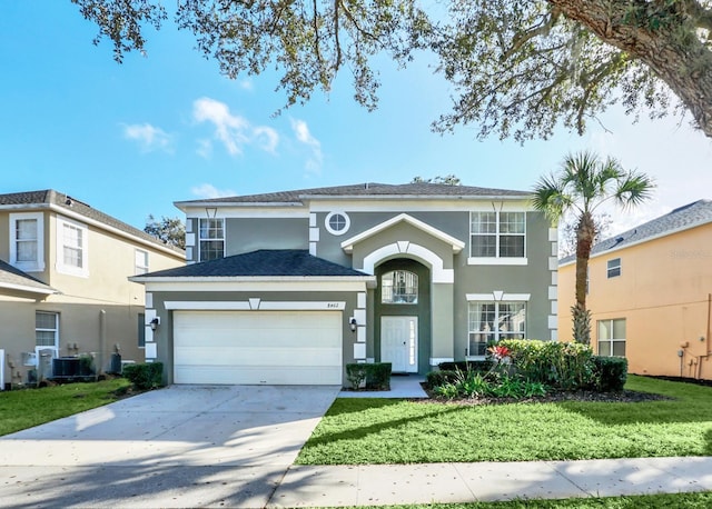 traditional home featuring central air condition unit, a garage, driveway, stucco siding, and a front lawn