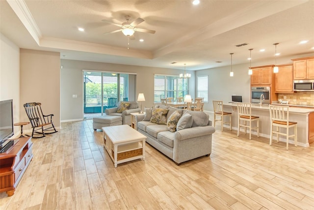 living room with light wood-style flooring, a raised ceiling, and a wealth of natural light