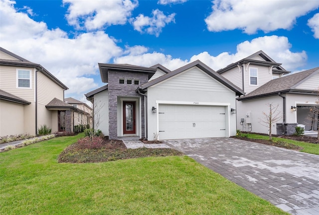 view of front of property featuring decorative driveway, an attached garage, central AC unit, a front yard, and stone siding