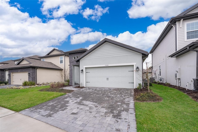 view of front of property with a garage, decorative driveway, a front lawn, and stucco siding