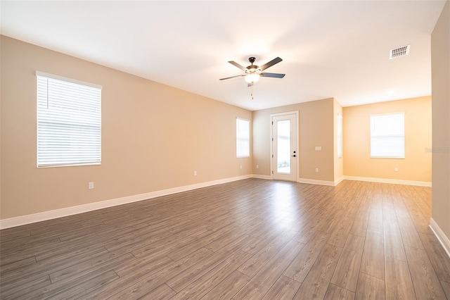 empty room featuring visible vents, ceiling fan, baseboards, and wood finished floors