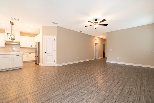 unfurnished living room featuring ceiling fan with notable chandelier, light wood-style flooring, visible vents, and baseboards