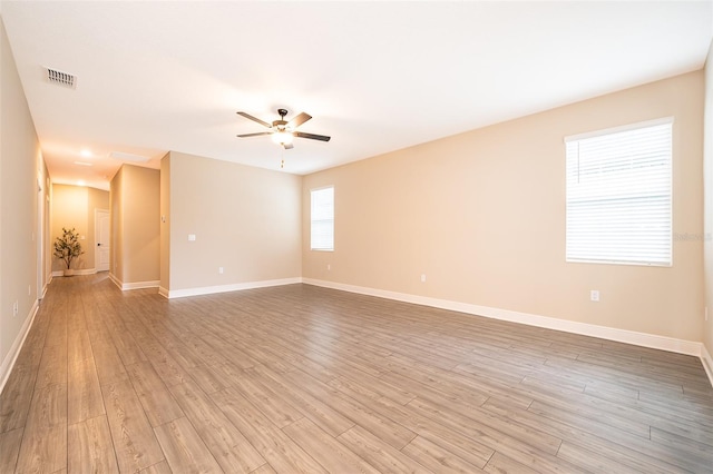 unfurnished room with light wood-type flooring, ceiling fan, visible vents, and baseboards