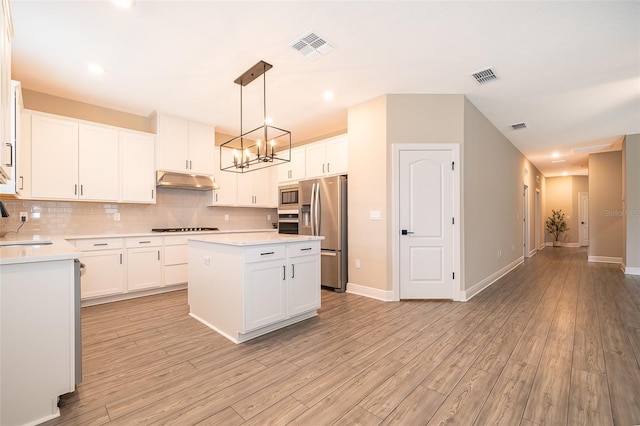 kitchen with stainless steel appliances, white cabinetry, light countertops, a center island, and pendant lighting