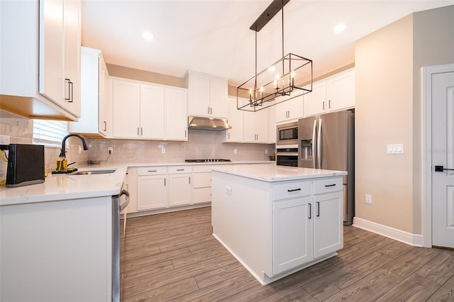 kitchen featuring a center island, stainless steel appliances, white cabinetry, a sink, and under cabinet range hood