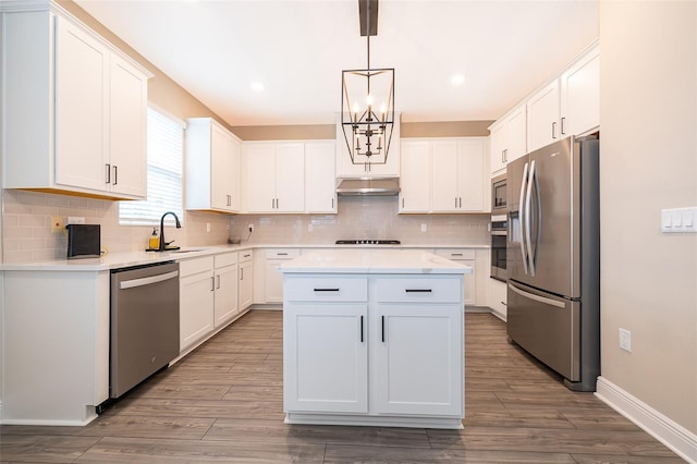 kitchen featuring appliances with stainless steel finishes, light countertops, hanging light fixtures, and white cabinetry