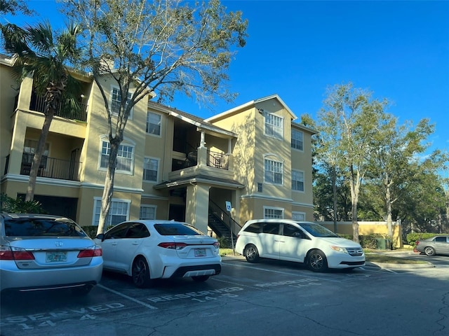 view of building exterior featuring stairs and uncovered parking