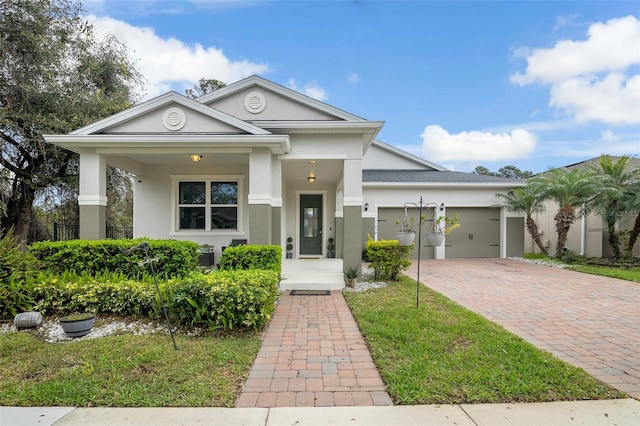 view of front facade with a front yard, decorative driveway, an attached garage, and stucco siding