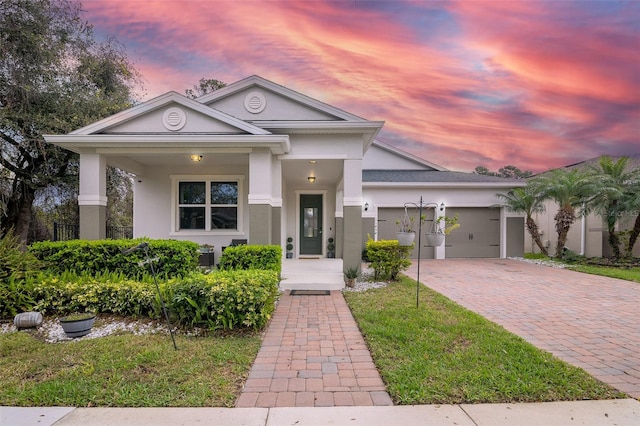 view of front of property with decorative driveway, an attached garage, a front yard, and stucco siding