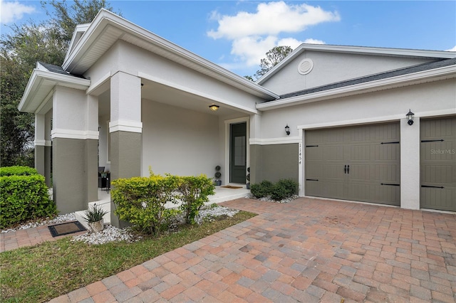 view of front of home featuring decorative driveway, an attached garage, and stucco siding