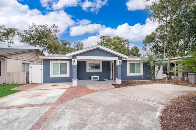 view of front of home with concrete driveway, fence, a gate, and stucco siding