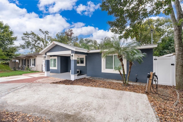 view of front of house with decorative driveway, fence, a gate, and stucco siding