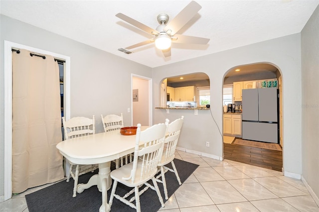 dining room with arched walkways, ceiling fan, baseboards, and light tile patterned floors