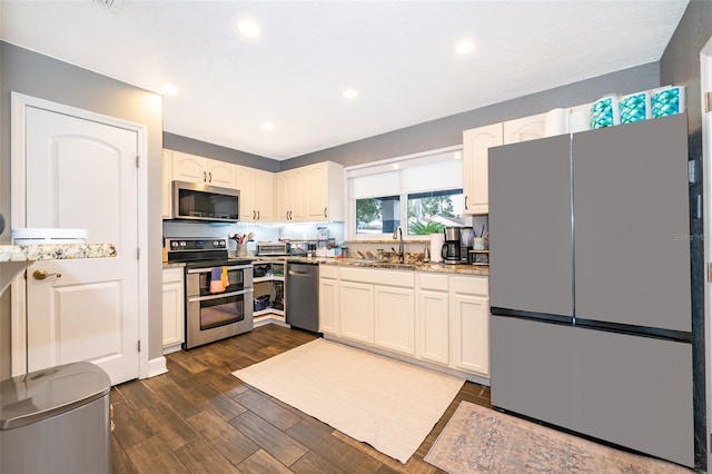 kitchen featuring dark wood finished floors, stainless steel appliances, recessed lighting, white cabinetry, and a sink