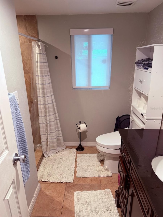 bathroom with toilet, baseboards, a tile shower, and vanity