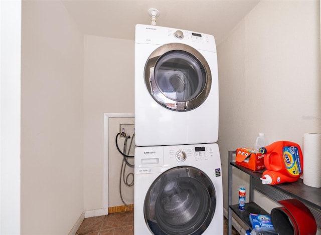 laundry room with laundry area, stacked washing maching and dryer, tile patterned flooring, and baseboards