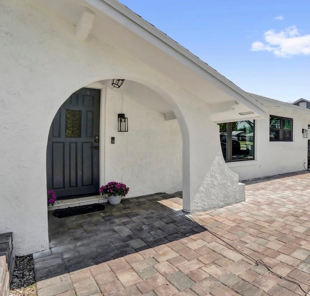 entrance to property featuring a patio and stucco siding