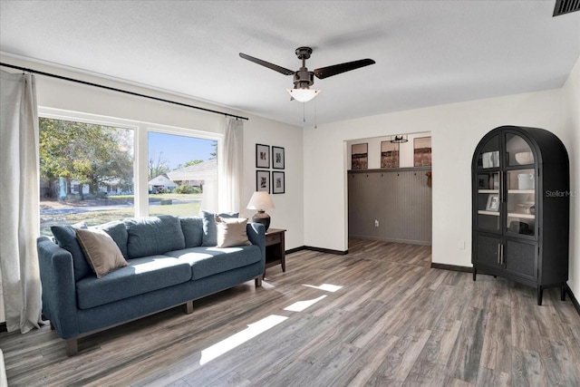 living room with visible vents, ceiling fan, light wood-style flooring, and baseboards