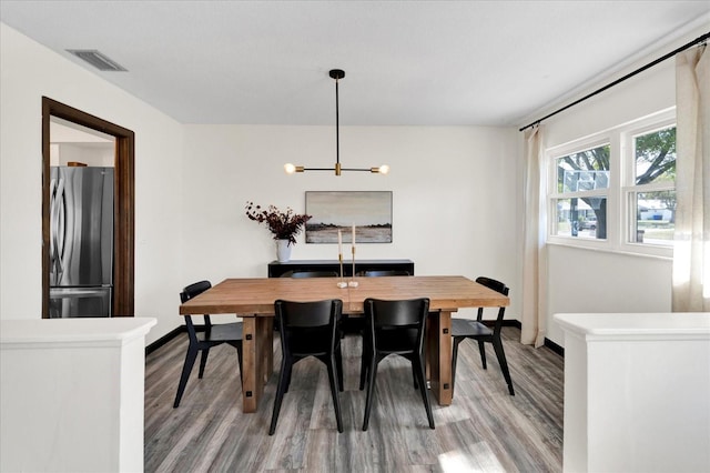 dining area featuring baseboards, a chandelier, visible vents, and light wood-style floors