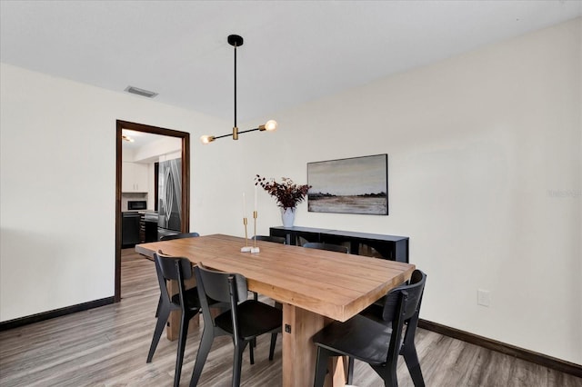 dining area with wood finished floors, visible vents, and baseboards