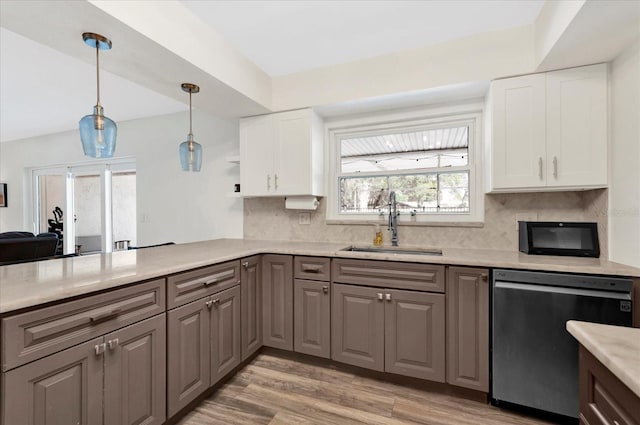 kitchen featuring a sink, white cabinets, light wood-style floors, light countertops, and stainless steel dishwasher