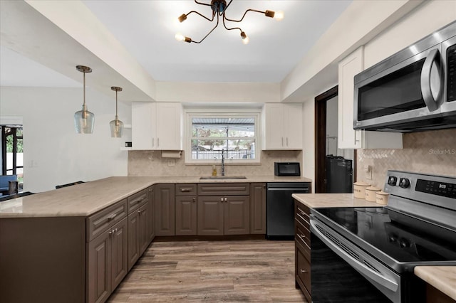 kitchen featuring appliances with stainless steel finishes, a wealth of natural light, white cabinetry, and a sink