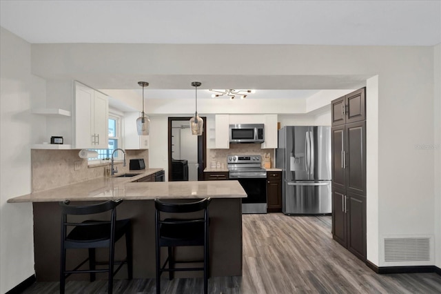 kitchen featuring a peninsula, a sink, visible vents, appliances with stainless steel finishes, and open shelves