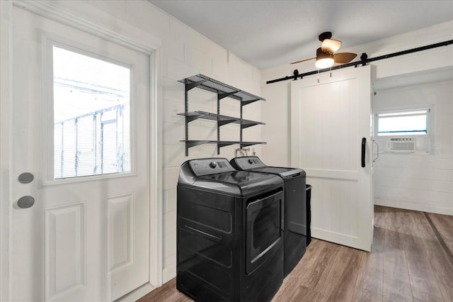 laundry area featuring laundry area, a barn door, wood finished floors, and washer and dryer